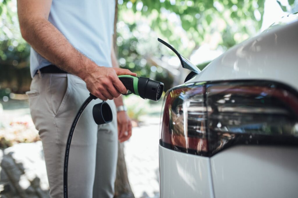 Hombre cargando un coche eléctrico en casa, ejemplo de la evolución del mercado de coches eléctricos en España