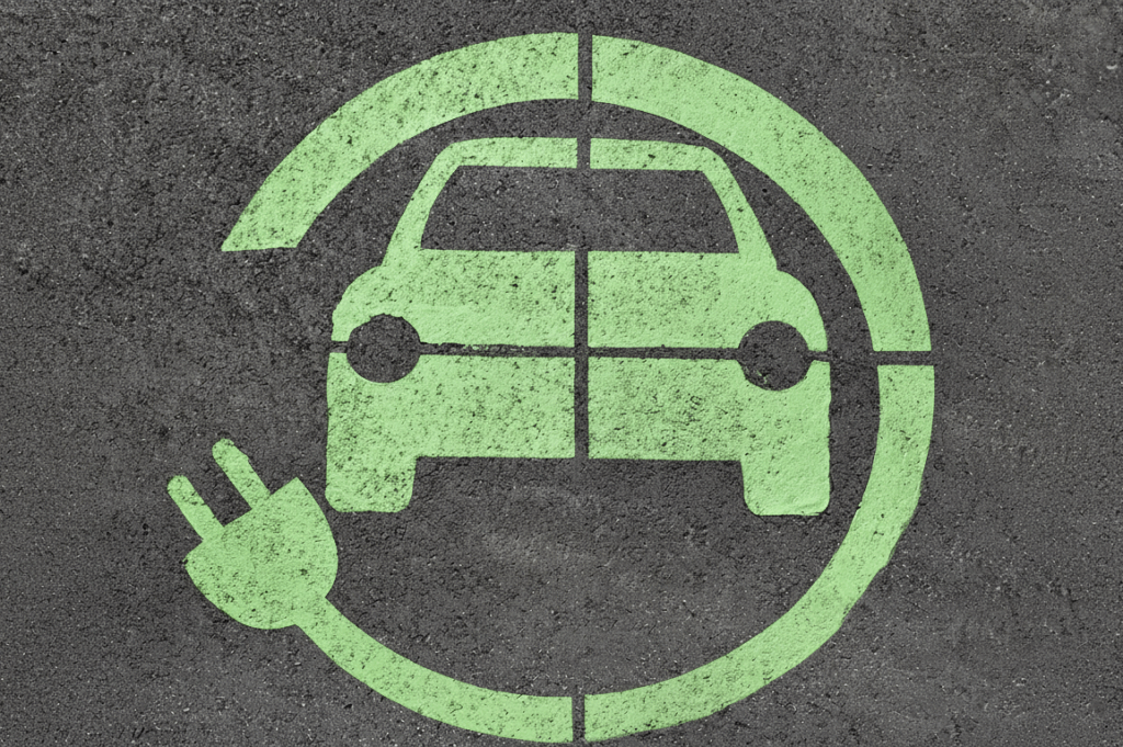 símbolo verde del coche eléctrico más eficiente con enchufe pintado sobre asfalto, señal de punto de recarga